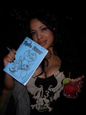 Undercover WitchesBrewPress agent on a mission to get club goers to pose with a Psycho Bunny comic. Here, a WitchesBrewPress undercover agent finds a willing target to pose. Photo by Michele Witchipoo, Dec. 2008 at LIT Lounge. 
